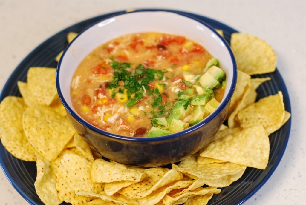 A bowl of tortilla soup surrounded by tortilla chips